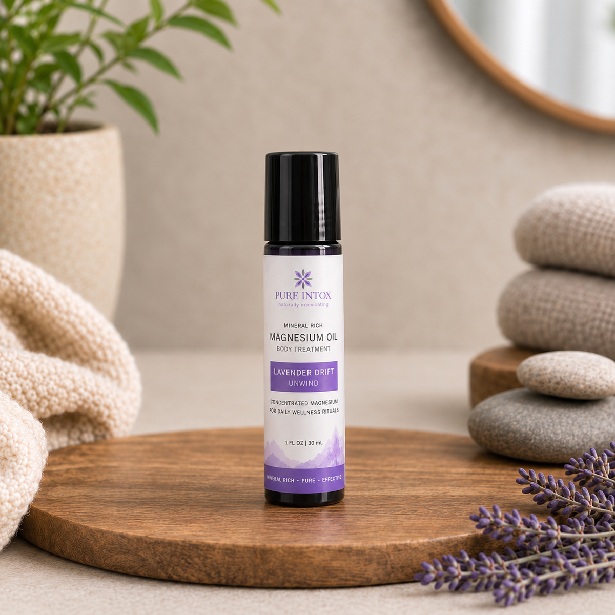 A 1 oz bottle of Pure Intox Magnesium Oil body treatment stands on a round wooden tray, styled with lavender sprigs, stacked stones, and a folded cream textile in a warm neutral setting.