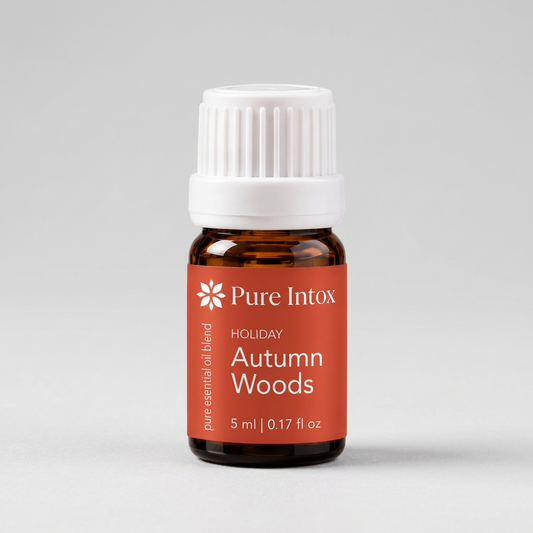 A 5 ml amber glass bottle of Pure Intox 'Holiday Autumn Woods' essential oil blend with a white ribbed cap and a terracotta orange label, set against a plain white background.