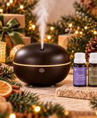 Pure Intox Quiet Evening aromatherapy gift set with Macaron Dark Wood Scentilizer, Organic Lavender and Frankincense Serrata essential oils in a warm holiday setting.