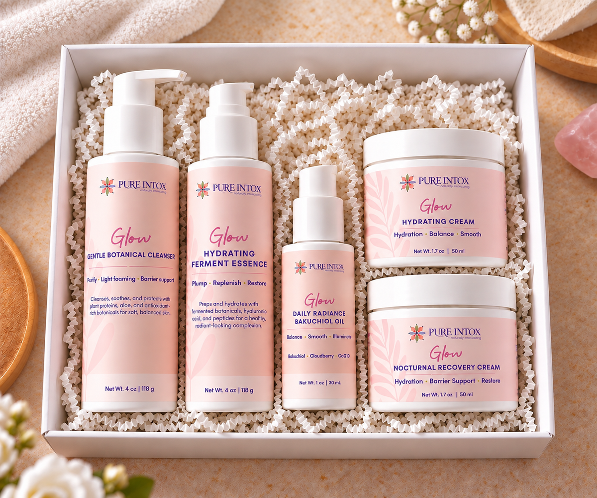 A boxed skincare set from Pure Intox, featuring five products in a white gift box filled with white crinkle paper. The set includes Gentle Botanical Cleanser, Hydrating Vitamin Essence, Daily Radiant Beauty Oil, Hydrating Cream, and Moisturizing Recovery Cream, all in soft pink packaging with white caps.