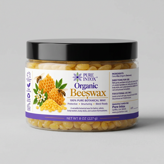 A jar of Pure Intox Organic Beeswax body balm with a black lid and a white label featuring illustrations of honeycomb, bees, and flowers. The jar is filled with pale yellow wax beads and is set against a plain white background.